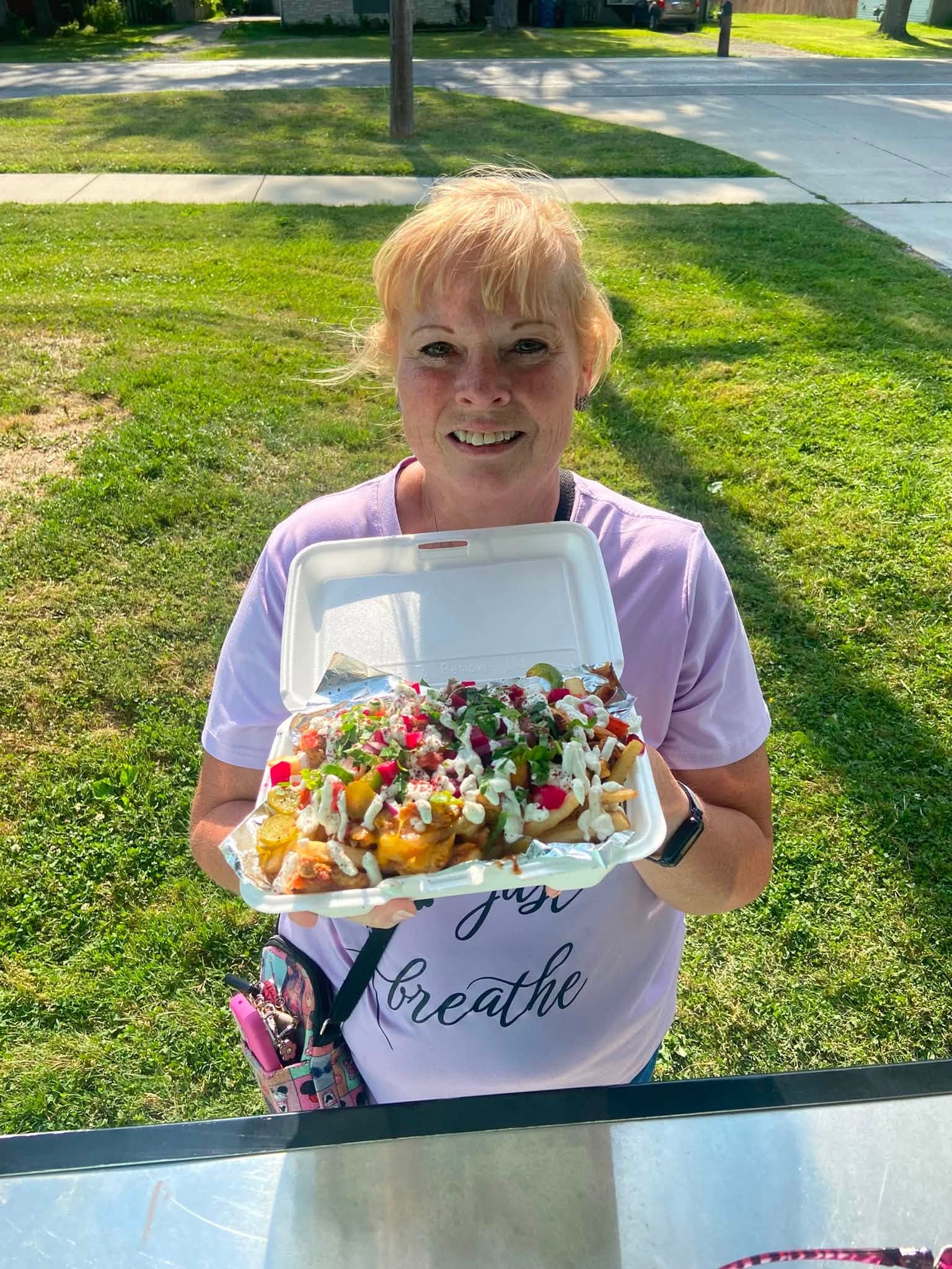 A customer at the window with a full tray of loaded shawarma fries